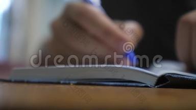 人在笔记本上写字.. 男人`用记事本写生活方式。 概念商业教育。 1.男人在房间里做笔记